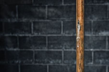 A grungy looking frozen copper pipe in a basement
