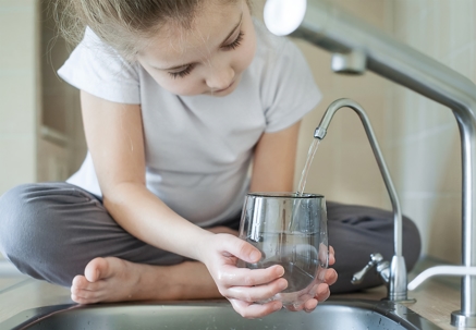 little girl filling glass of water from sink